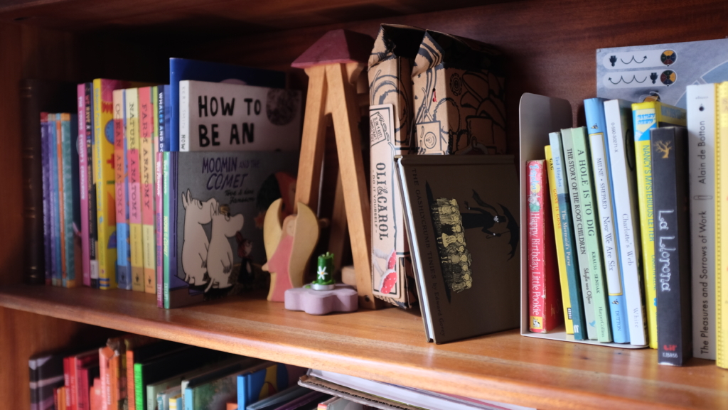 A messy bookshelf with a mix of toys and books