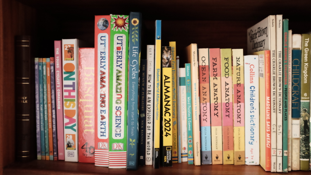 A section of a bookshelf showing the spines of reference books for kids.